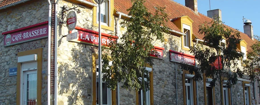 Façade en pierre de la Brasserie La Pierre au soleil, avec les enseignes « Café-Brasserie », « La Pierre » et « Café Edwige »