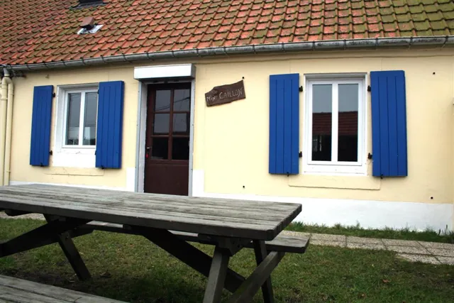 Façade de la maison Min Caillon, volets bleus, et table de jardin
